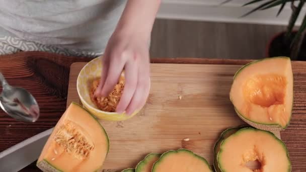 女人的手从种子上清洁甜瓜 厨房背景 — 图库视频影像