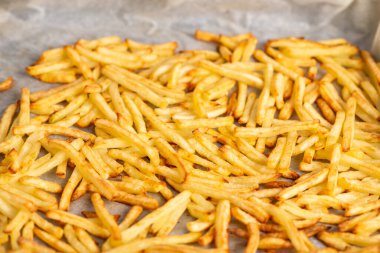 Kızarmış patates kızartması kabartma kağıdının üzerinde duruyor. Fırında donmuş patates kızartması pişirmek.