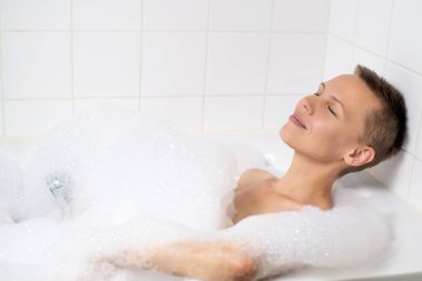 Lüks köpük banyosu yapan orta yaşlı bir kadın.