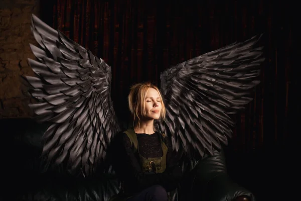A woman with black angel wings represents the power of temptation