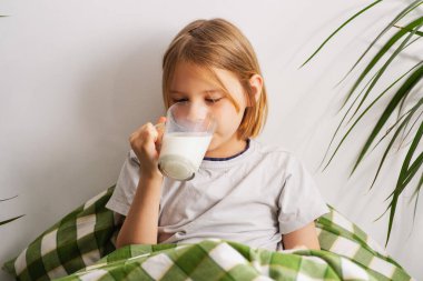 Yatakta uzanmış, 9-10 yaşındaki bir çocuk bir bardak sütün tadını çıkarıyor, zihni rüyalarda geziniyor, anın huzurunu kucaklıyor.
