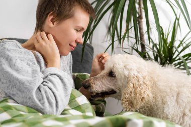 Gün boyunca, orta yaşlı bir kadın, saçları kısa kesilmiş, büyük kanişiyle yatakta uzanıyor. Hareketsizlik, hafta sonu rahatlığı