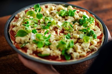 Bol peynirli çiğ pizza ve yuvarlak şekilli şifalı bitkiler. Vejetaryen pizza..