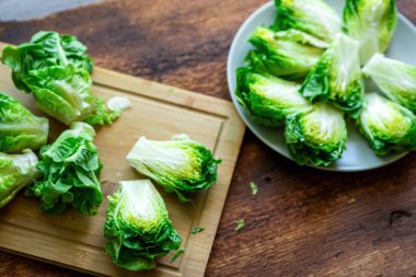 Tahta kesme tahtasının üzerinde ikiye bölünmüş taze yeşil marul. Yukarıdan bak. Vejetaryen yemeği. salata hazırlama.