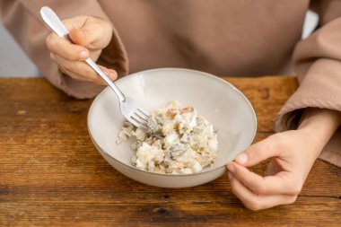 Mayonezli iyilik: Kremalı mayonez ve renkli sebzelerle bezenmiş, çatal dolusu lezzetli salata yiyen bir kadın.