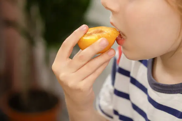 Plum perfection: A child indulges in the perfection of a ripe yellow plum, recognizing the nutritional benefits of this fruity indulgence