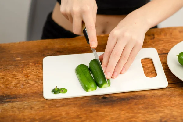 Culinary wellness: Female hands expertly cut green cucumbers, illustrating the culinary wellness achieved through salad preparation and the nutritional value of vegetables