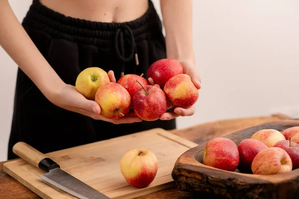 Woman\'s hands and a collection of fresh red apples on a wooden background evoke the invigorating freshness of healthy eating, vegetarianism, and the nutritional value of fruits