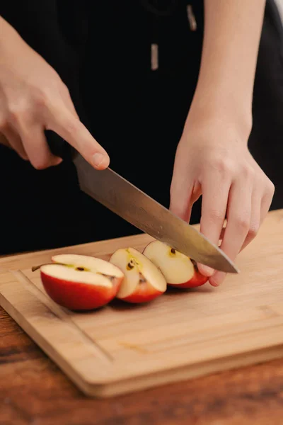 Female hands skillfully prepare a red apple on a wooden board, exemplifying the bounty of health, vegetarian choices, and the nutritional perks that come from embracing fruits