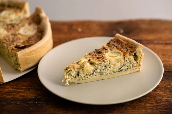 Comfort Food Bliss: A comforting leek quiche adorned with eggs graces the wooden surface, promising a taste of nostalgia