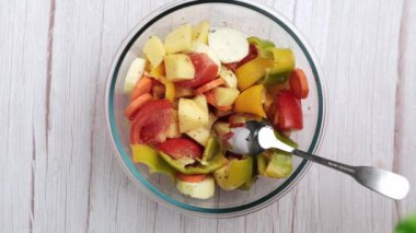 Çeşitli sebzeler, patatesler, biberler, havuçlar ve kabaklar bir kasede ustalıkla bir araya getirilirler.