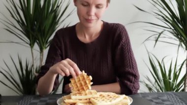 Orta yaşlı bir bayan Belçika Waffle 'ının tadını çıkarıyor, ona lezzetli bir kahvaltı hazırlıyor ya da öğle yemeği hazırlıyor.