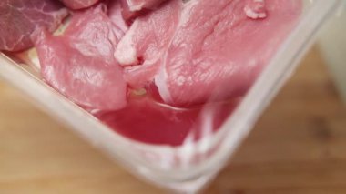 İçinde bozuk domuz eti parçaları ve kan birikintileri olan plastik konteynır, yanlış depolama ve süresi geçmiş raf ömrünü açıkça gösteriyor.