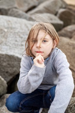 10 yaşındaki bir çocuğun düşünceli davranışı heybetli taşlara dikkatle oturmuş.