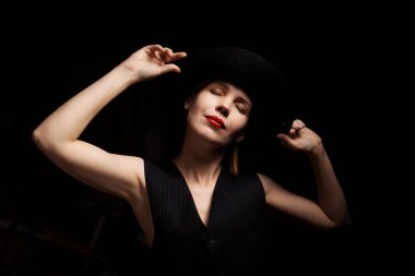 Siyah arka planda şapkalı orta yaşlı bir kadın. Kırklı yaşlarda hoş bir kadın. Hayal, fantezi konsepti.