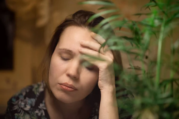A middle-aged woman smokes. Surrounded by green plants. Fatigue, burnout, relaxation concept.