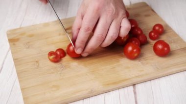 Tahta kesme tahtasının üzerinde vişneli domates dilimliyorum.