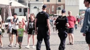 Varşova, Polonya - 20 Temmuz 2023: İki polis ve bir çok insan Eski Şehir caddesi boyunca yürüyor