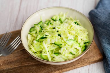 Ahşap bir tabakta lahana ve salatalık bulunan taze ve renkli bir vejetaryen lahana salatası.