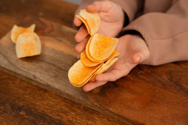 Patates kızartması: Bir insanın elleri gevrek bir aperatifle, masa yayılmış..