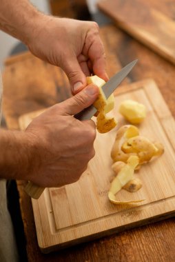 Şef patates soyuyor, yemek için malzeme hazırlıyor..