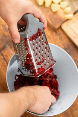 Hazırlanan malzemeler: rendelenirken canlı pancar lekeli eller.