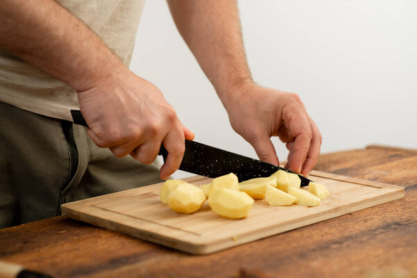 Preparing ingredients: dicing potatoes on a bamboo chopping board.