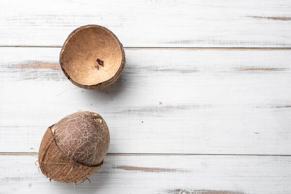Two coconuts are on a white background. One is whole and the other is cut in half