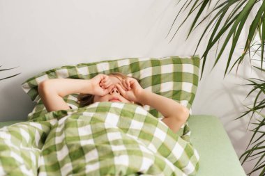 Yumuşak ışıkta, bir çocuk yatağında uykusunu siliyor. Sabah erken kalkar