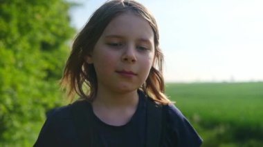 Bir tarlada duran genç bir kız, güneş yüzünde parıldarken düşüncelere dalmış..