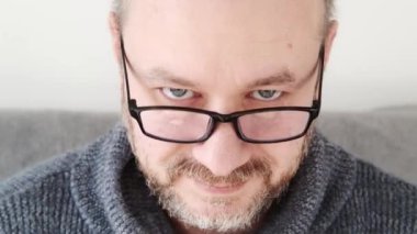 Göğsünden vurulmuş gözlüklü bir adamın yakın plan portresi..