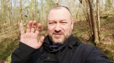 Bir adam güneşli bir öğleden sonra ormanda keyifli bir yürüyüş yapar..