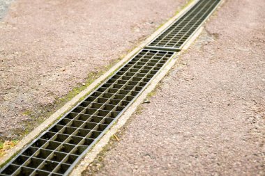 Dışarıdaki Asphalt Yolu 'ndaki drenaj ızgarası; Kamu Hizmetleri Altyapısı ve Kentsel Bakım.