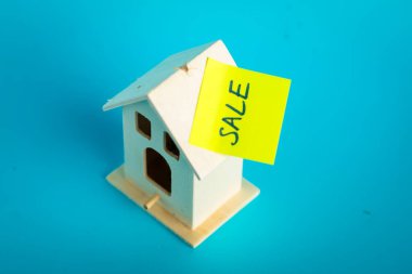 Mavi arka planda indirim etiketli minyatür ev.