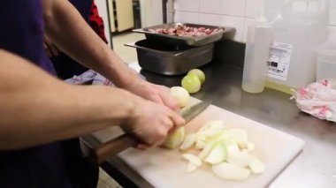 Aşçı usta bir şekilde profesyonel bir mutfak ortamında soğan doğruyor..