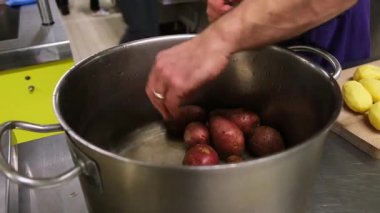 Şef, profesyonel bir mutfak ortamında yemek pişirmek için patatesleri ustalıkla hazırlar..