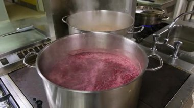 Endüstriyel mutfak ortamında kaynayan mor sıvı, enerjik hareket ve kaynayan aksiyonlar..