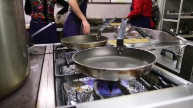 Kızartma tavaları ve aşçılar malzemelerini hazırlamakla meşgul..
