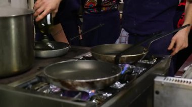 Aşçı, mutfak ortamında tavada zeytinyağı hazırlıyor..