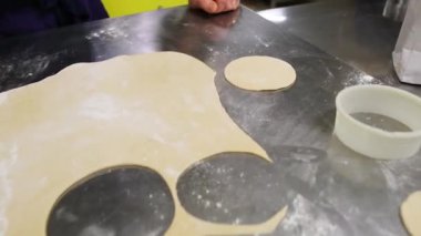 Fırıncı paslanmaz çelik tezgahta taze hamur işleri için hamur daireleri kesiyor.