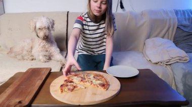 Keyifli köpek eşliğinde kanepe macerasında pizza yiyen bir kız..