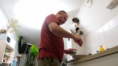 Modern bir mutfakta yemek pişiren adam kırmızı gömlekli yemek pişirme sahnesi.