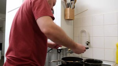 Adam mutfakta akıllı telefonları kontrol ederken yemek pişiriyor..