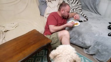 Kanepede yemek yiyen adama yaklaşan meraklı köpek, komik bir yemek zamanı yaratıyor..