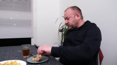 Adam evde yemek masasında akıllı telefonlara bakarken yemeğin tadını çıkarıyor..