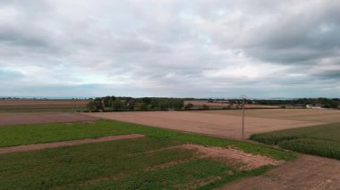 Dramatik gökyüzü altında geniş kırsal alanlarda İHA uçuşu geniş tarım arazilerini ele geçiriyor.