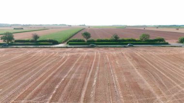 Yeşil yemyeşil tarlaların havadan görünüşü ve kırsal yol trafiği ile hasat edilen arazi.