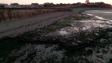 Gün batımında sakin kıyı şeridi çekilen gelgitleri ve genişleyen okyanus ufkunu yakalıyor..