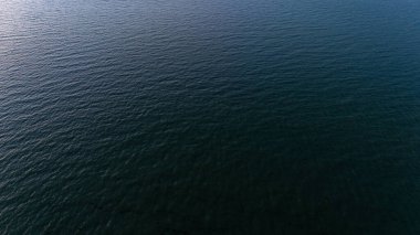 Sakin açık deniz bulutlu gökyüzünün altında yumuşak dalgalarla.