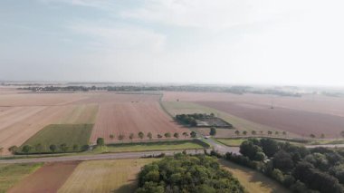 Uçsuz bucaksız tarım arazileri ve kırsal yolda giden arabanın havadan görünüşü.